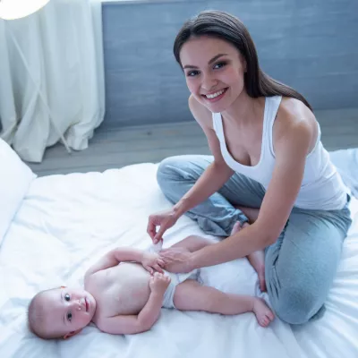 A mother changes her baby on a comfy bed