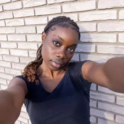 young person taking selfie against brick wall