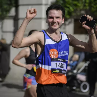 man in centrepoint vest running a marathon and cheering