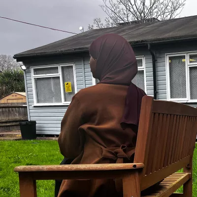 Young person in headscarf in side profile by a scout hut