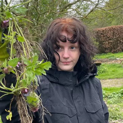 Young person holding up a bunch of weeds on a biodynamic farm