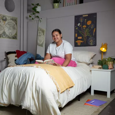 Mia smiling on her bed in a Centrepoint service whilst reading