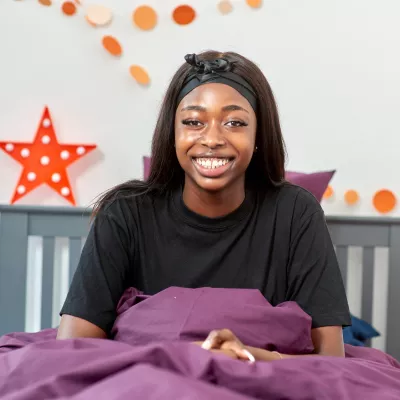 A young person sits in a cosy bed