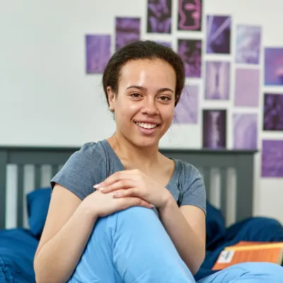 A young person sits on a cosy bed in a Centrepoint service