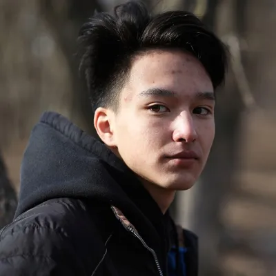Young man in woody park looking over his shoulder to the viewer.