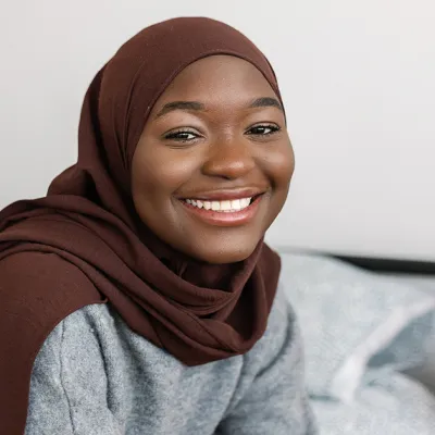 Young women smiling on her bed in her Centrepoint Room.