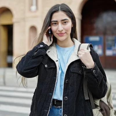 A young woman makes a phone call from the street.