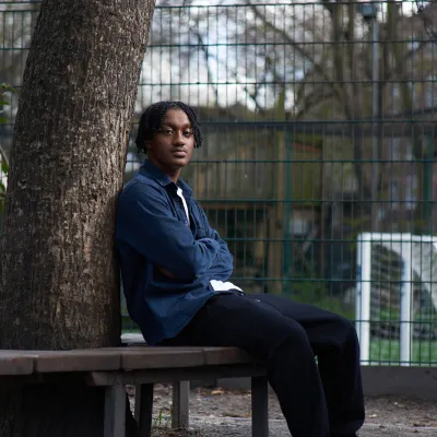 Young person sitting next to a tree