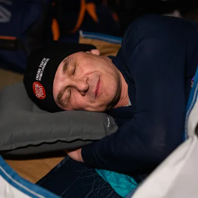 Sleep out participant in sleeping bag with eyes closed. 