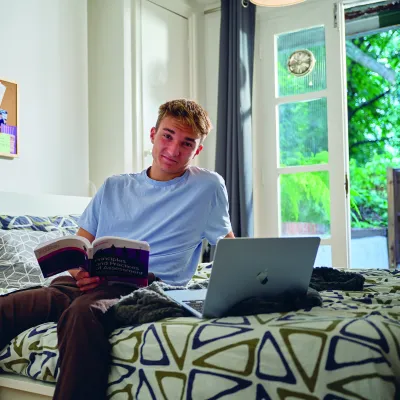 Young man sat on a bed smiling