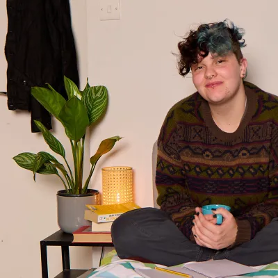 A young person sits on a bed in their supported accommodation
