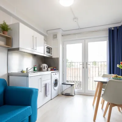 Living room with blue chair, kitchen and small table