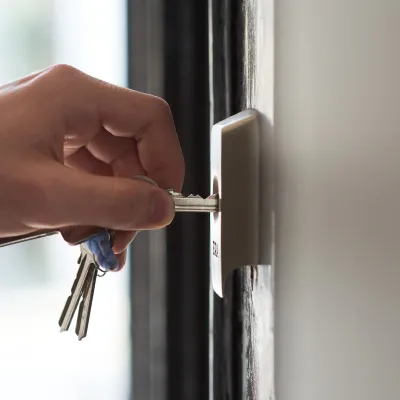 Hand putting a key into a door lock