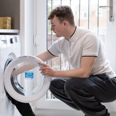 A young person loads the washing machine in supported housing