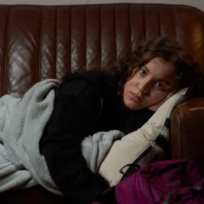 Young person sleeping on friend's sofa