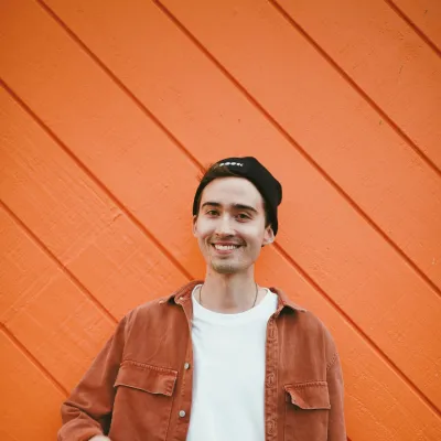 Young man smiling in front of an orange wall