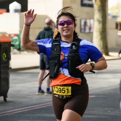 Image of a woman waving her hand as she runs past 