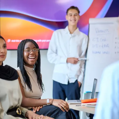 Smartly dressed young people laugh in an office meeting