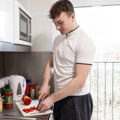 A young person prepares food in a kitchen in their new home