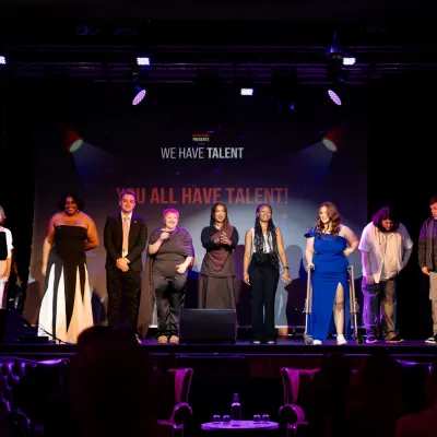 A group of young people stand in the spotlight on stage at Centrepoint Presents